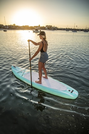 woman in blue and white shorts riding on white and green surfboard during daytime