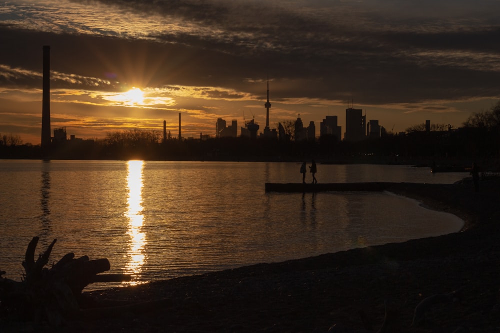 silhouette of people on dock during sunset