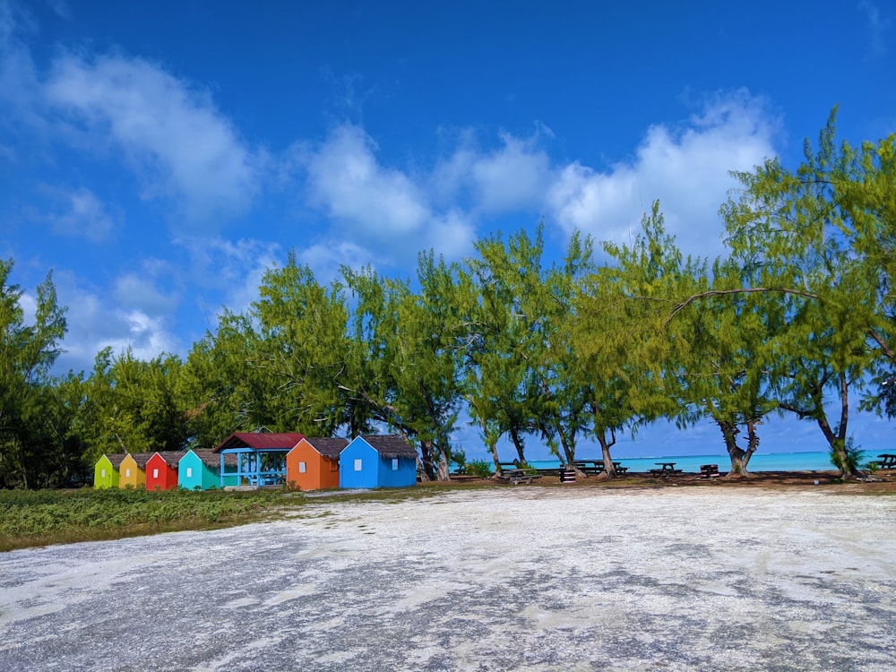 blue and green houses on white sand under blue sky during daytime