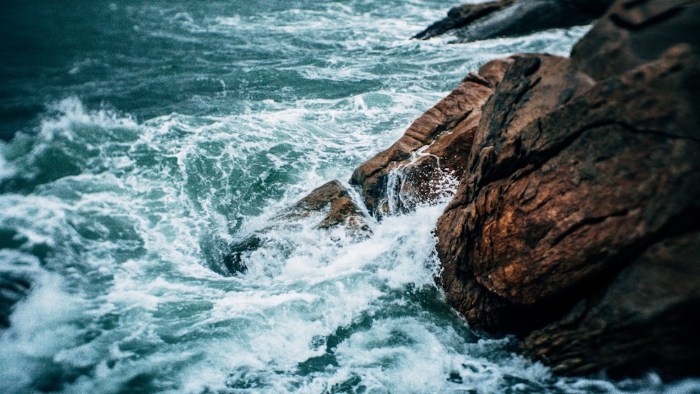 brown rocky mountain beside body of water during daytime