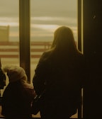 woman in black coat standing near window