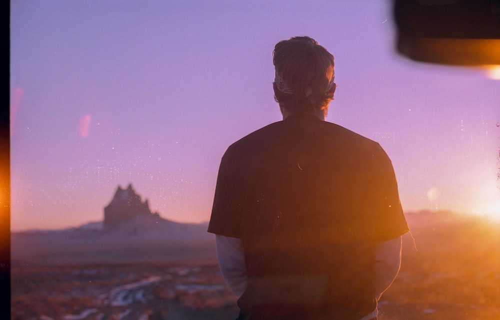 man in black shirt standing on rock during daytime