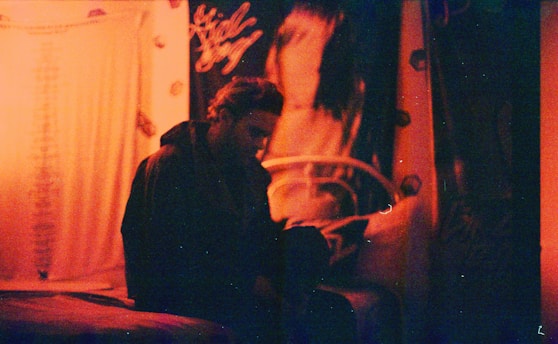 A cozy dark-themed room with a glowing neon orange anime poster on the wall.