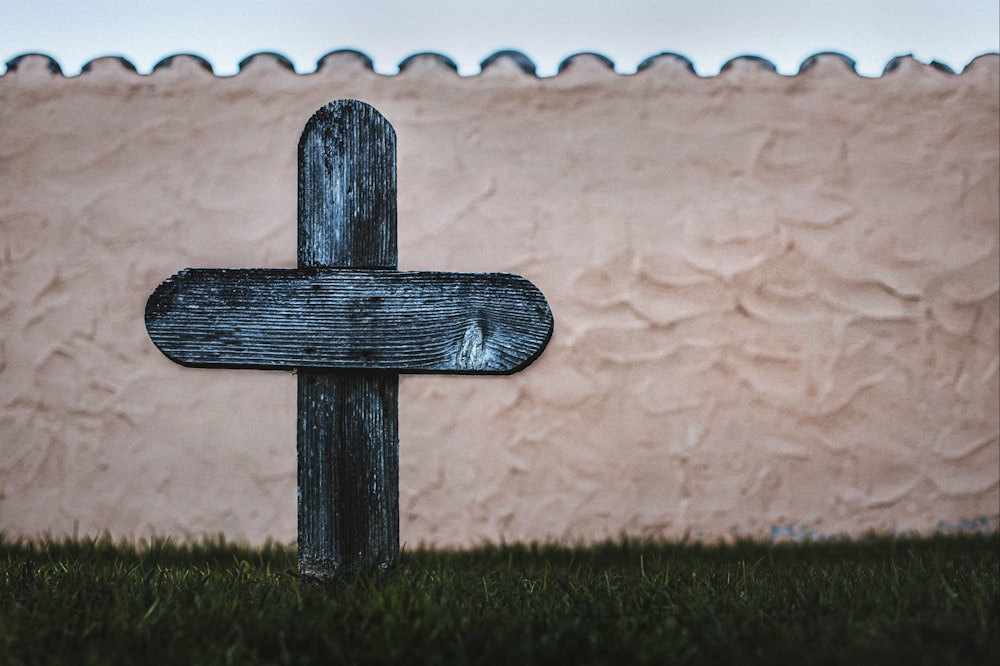 a wooden cross in front of a pink wall