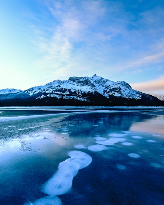 snow covered mountain near body of water during daytime in Abraham Lake Canada