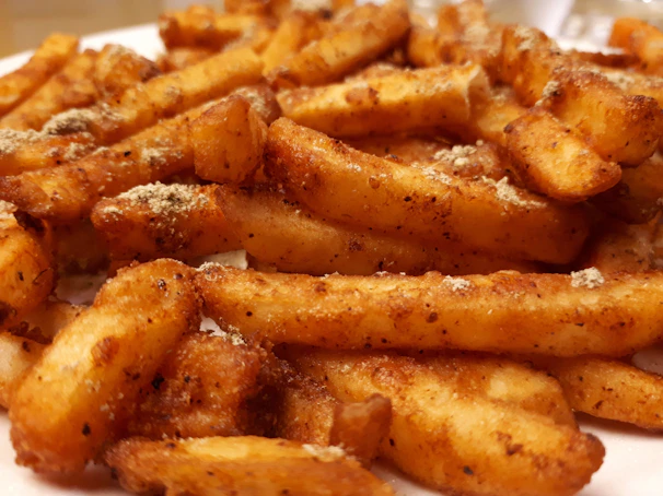 A tray of perfectly cut frozen fries ready to be cooked, with seasoning sprinkled on top