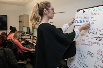 woman in black blazer writing on white paper