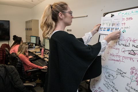 woman in black blazer writing on white paper