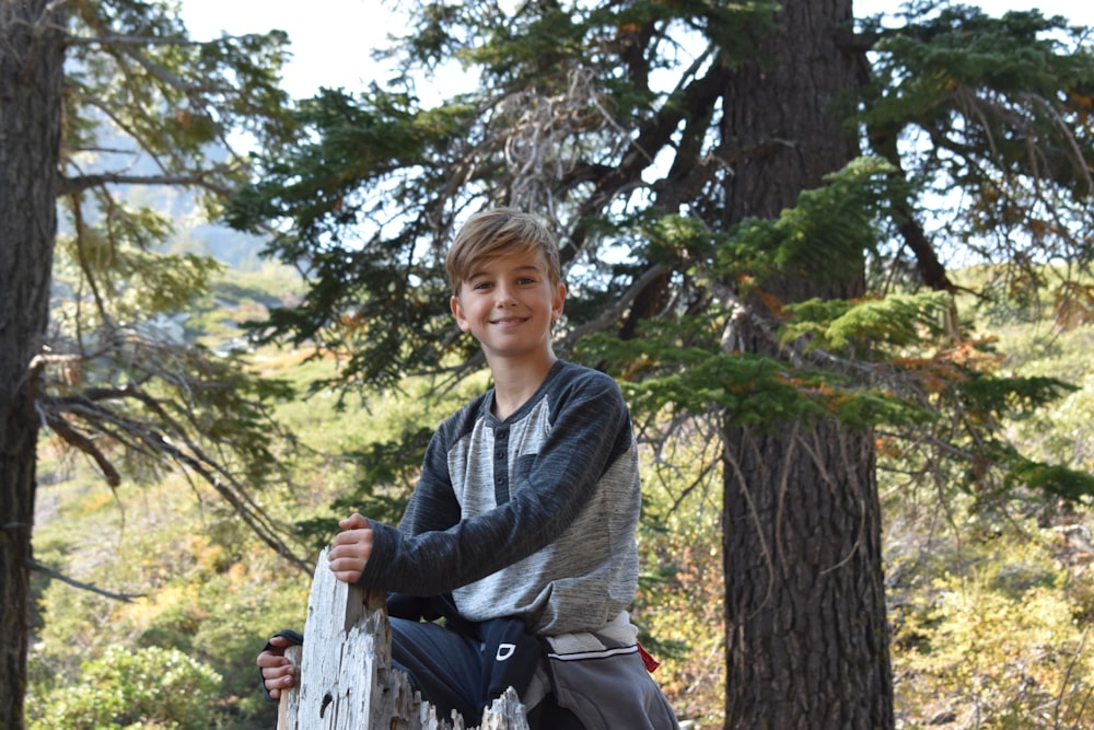 woman in gray and black long sleeve shirt standing near brown tree during daytime