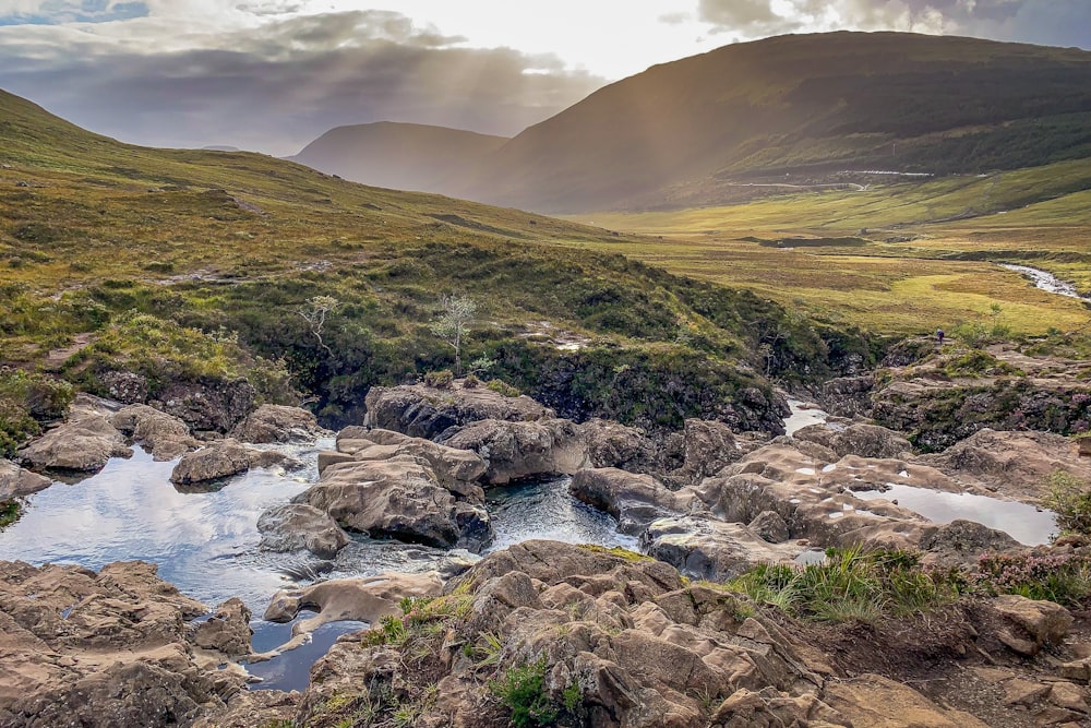 Fluss zwischen grünem Grasfeld unter weißen Wolken tagsüber