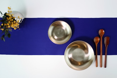 A set of polished tuning forks arranged neatly on a wooden table.