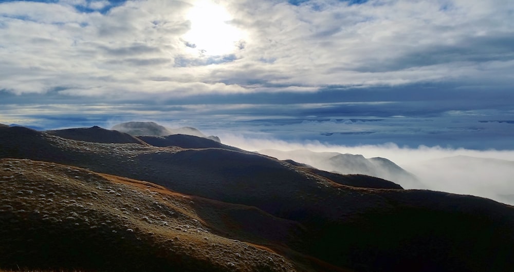 brown and green mountains under white clouds and blue sky during daytime