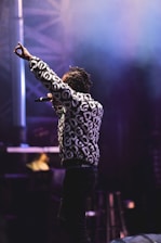 Jo Tan performing on stage with expressive gestures and a warm smile.