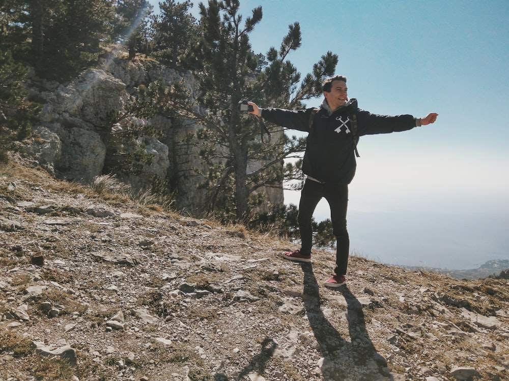 woman in black jacket standing on rocky ground during daytime