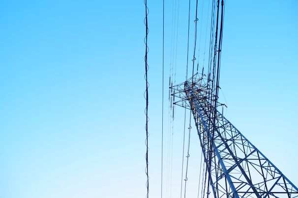 Close-up of a high-voltage transmission tower against a clear sky, symbolizing robust energy infrastructure.