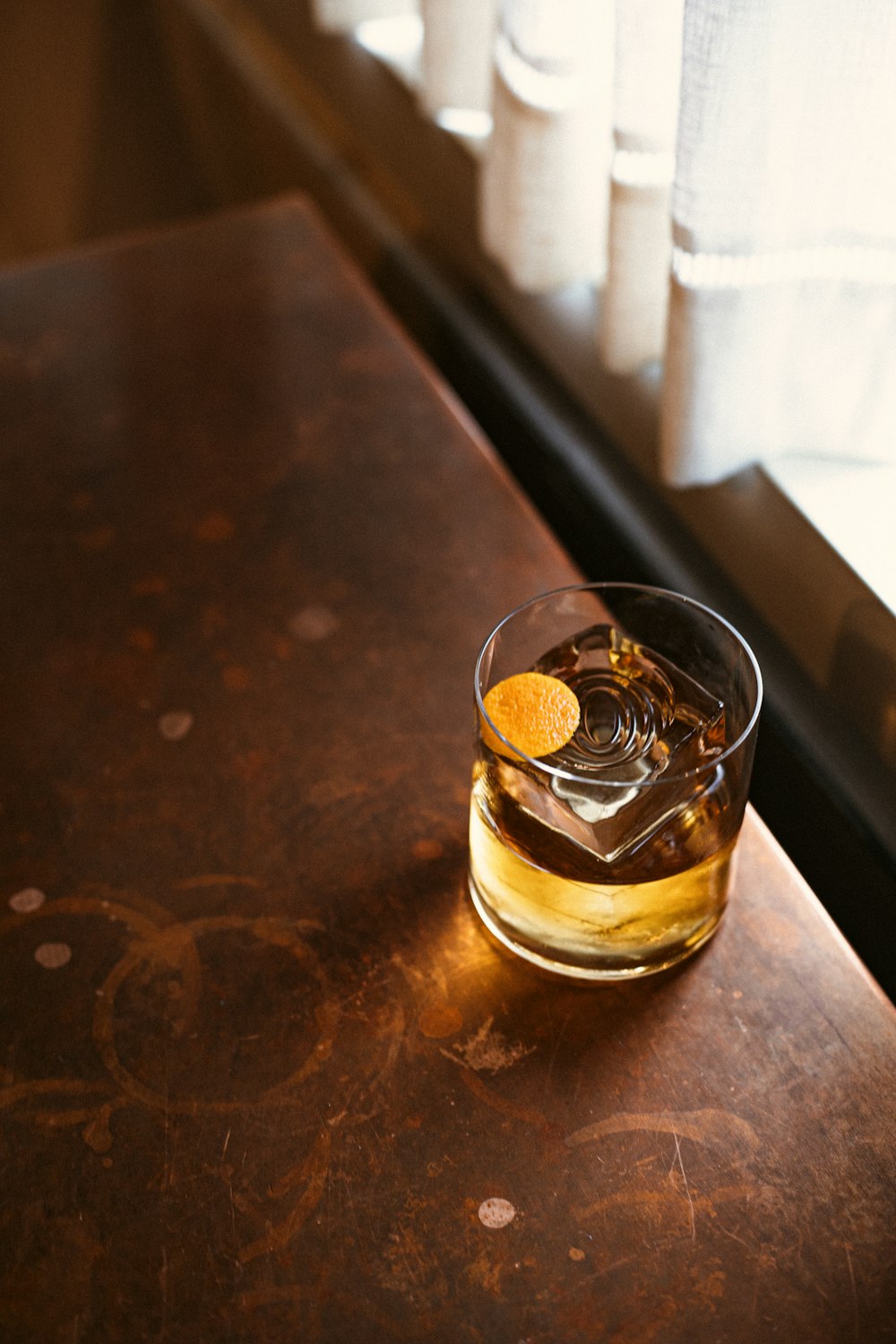 bicchierino trasparente con liquido marrone su tavolo di legno marrone