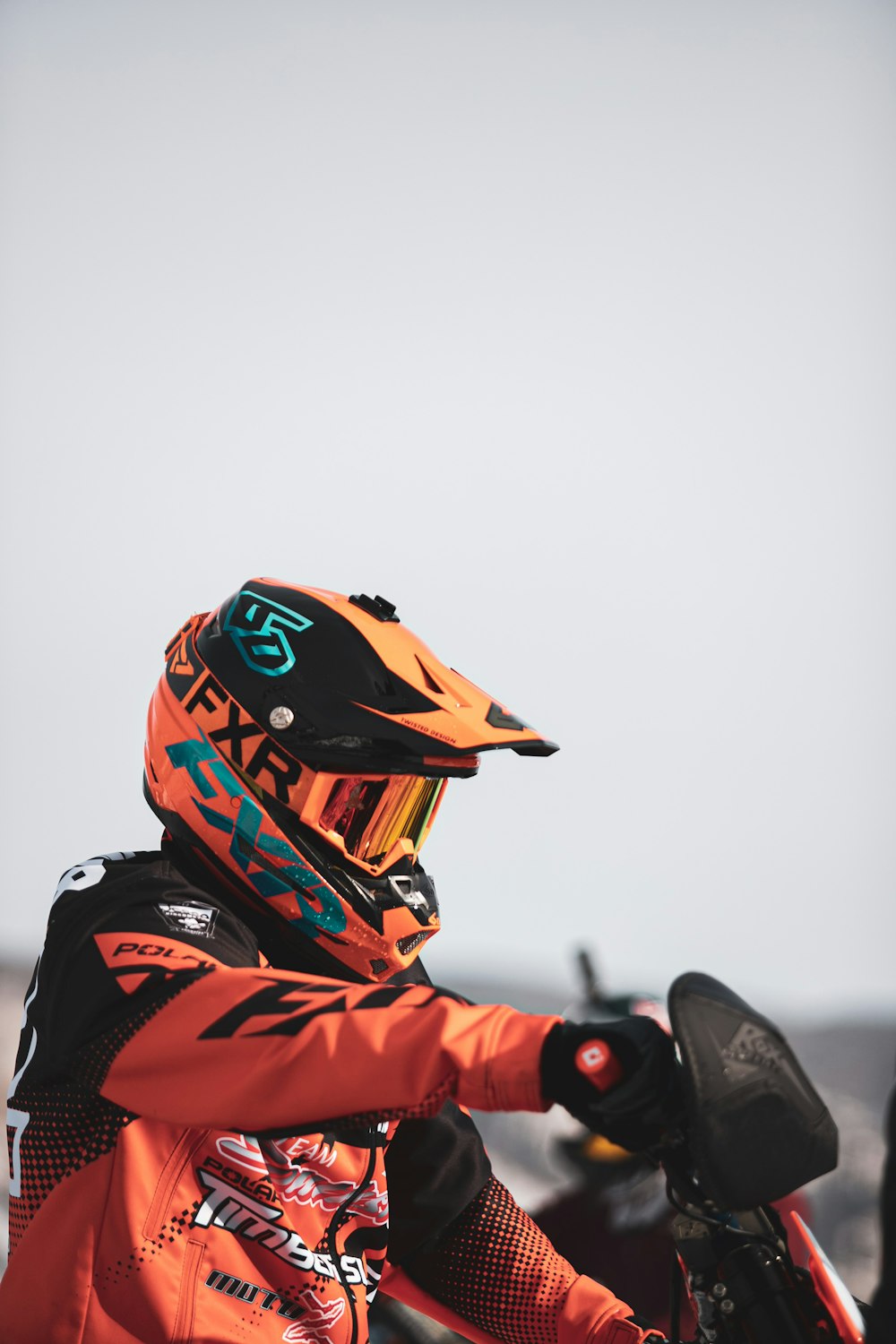 person in orange and black jacket wearing black helmet