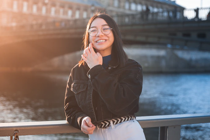 woman in black jacket and white pants standing on a city pavement