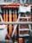 A close-up of a thick metal wire is in focus with a blurred construction site in the background. The construction site features orange and gray scaffolding and materials.
