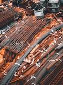 A collection of metal rods and bars are organized on the ground, tied together with what appear to be white straps. Some of these metal pieces form grid-like structures, likely reinforcing wire meshes. The setting conveys a scene typical of a construction site, where materials are being prepared or stored for use.
