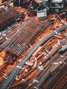 A collection of metal rods and bars are organized on the ground, tied together with what appear to be white straps. Some of these metal pieces form grid-like structures, likely reinforcing wire meshes. The setting conveys a scene typical of a construction site, where materials are being prepared or stored for use.