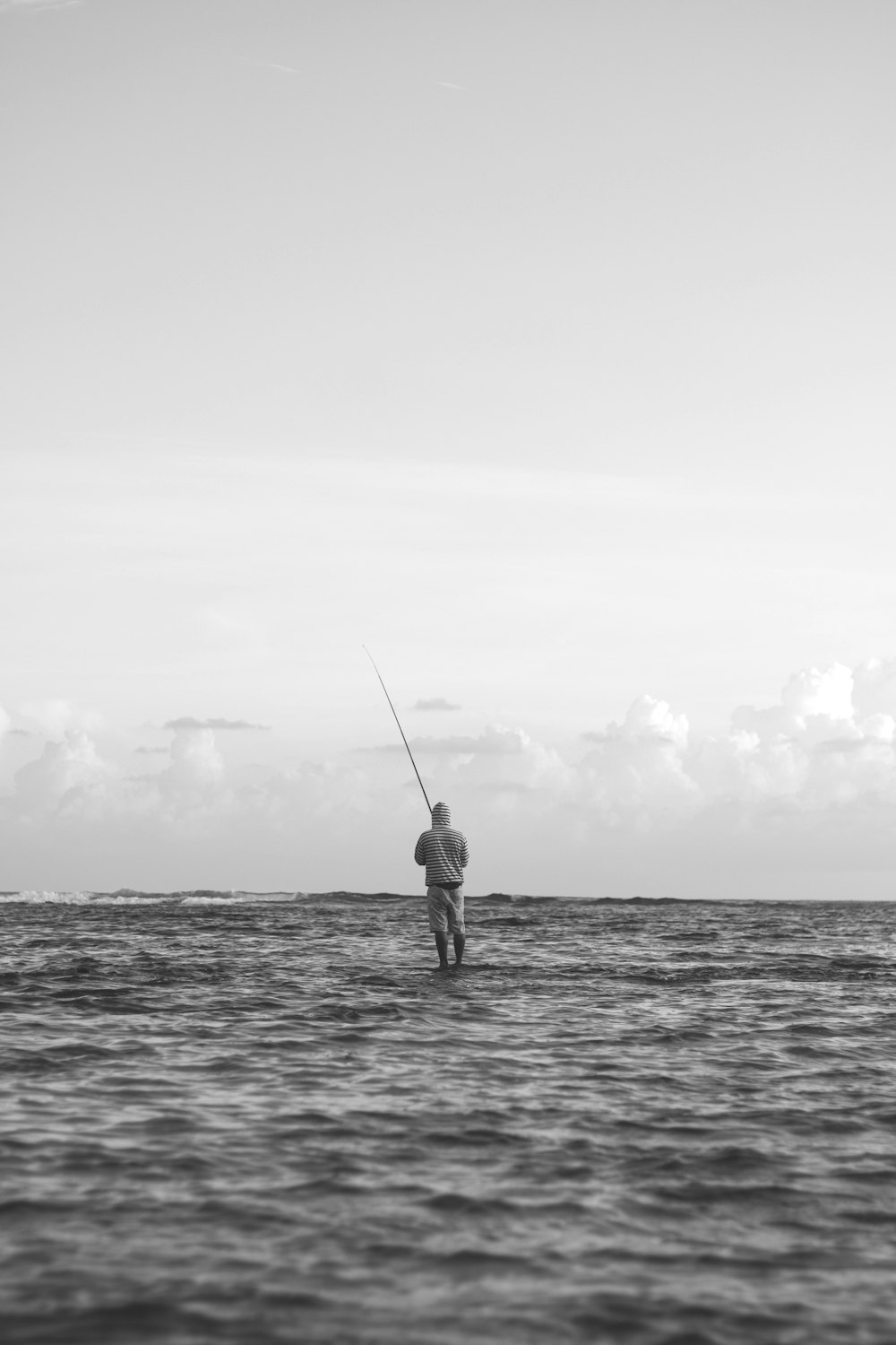 grayscale photo of person fishing on sea