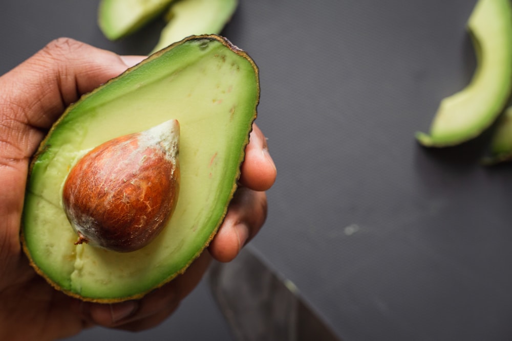 personne tenant des fruits tranchés verts et bruns