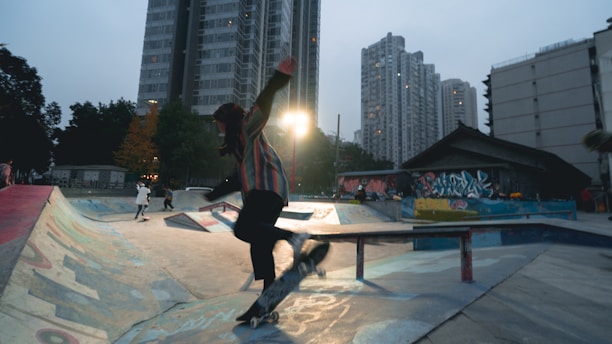 A skater performing a trick on a graffiti-covered urban ramp in Granada at sunset.