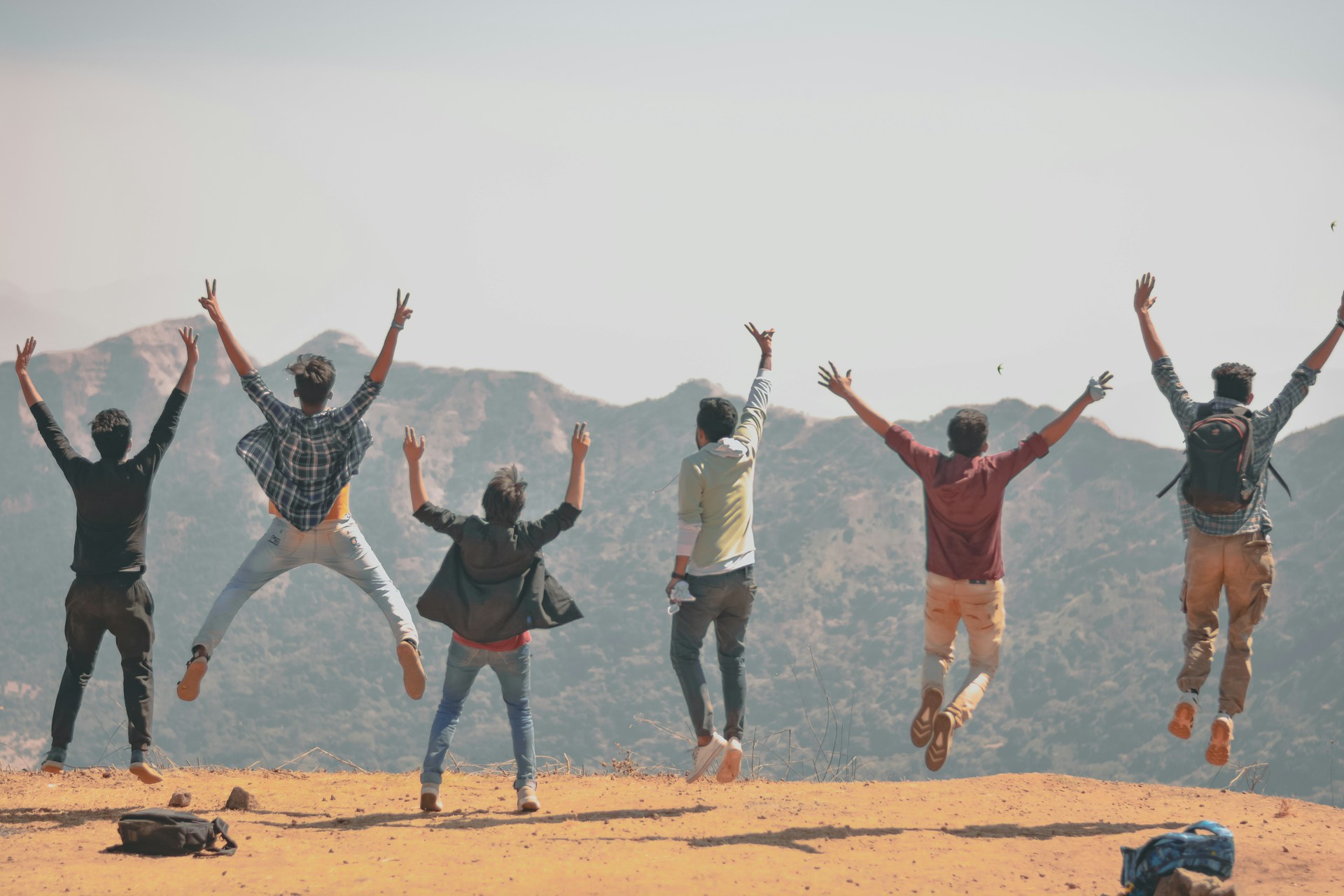 group of people jumping on brown sand during daytime