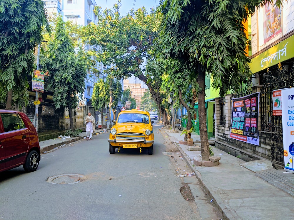 yellow car on road near green trees during daytime