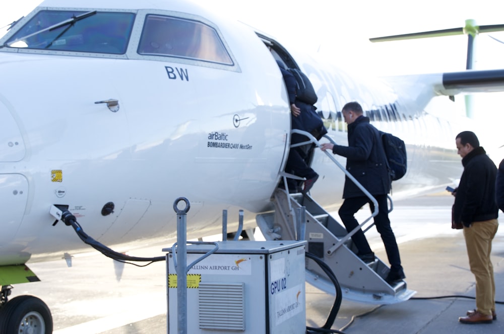 man in black jacket standing beside white airplane