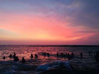 A colorful beach sunset with travelers relaxing and soaking in the golden light.