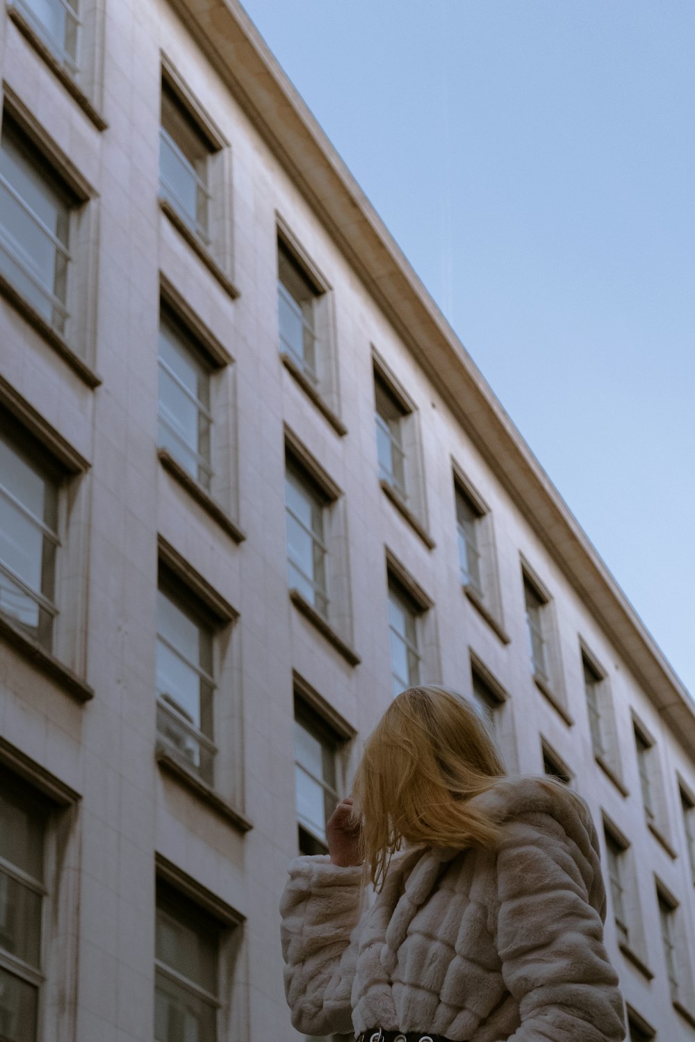 woman in white shirt standing near white concrete building during daytime