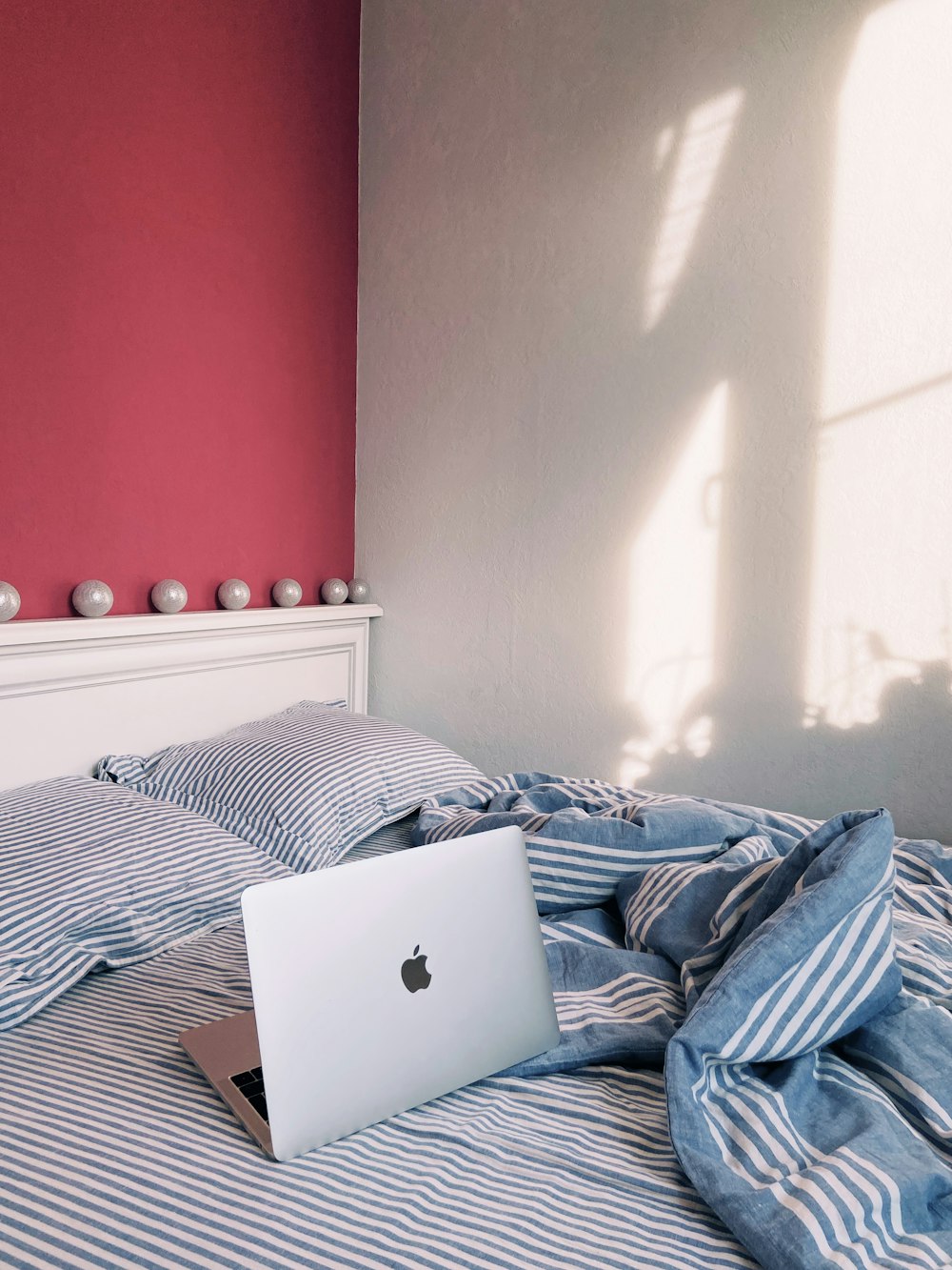 silver macbook on blue and white bed linen