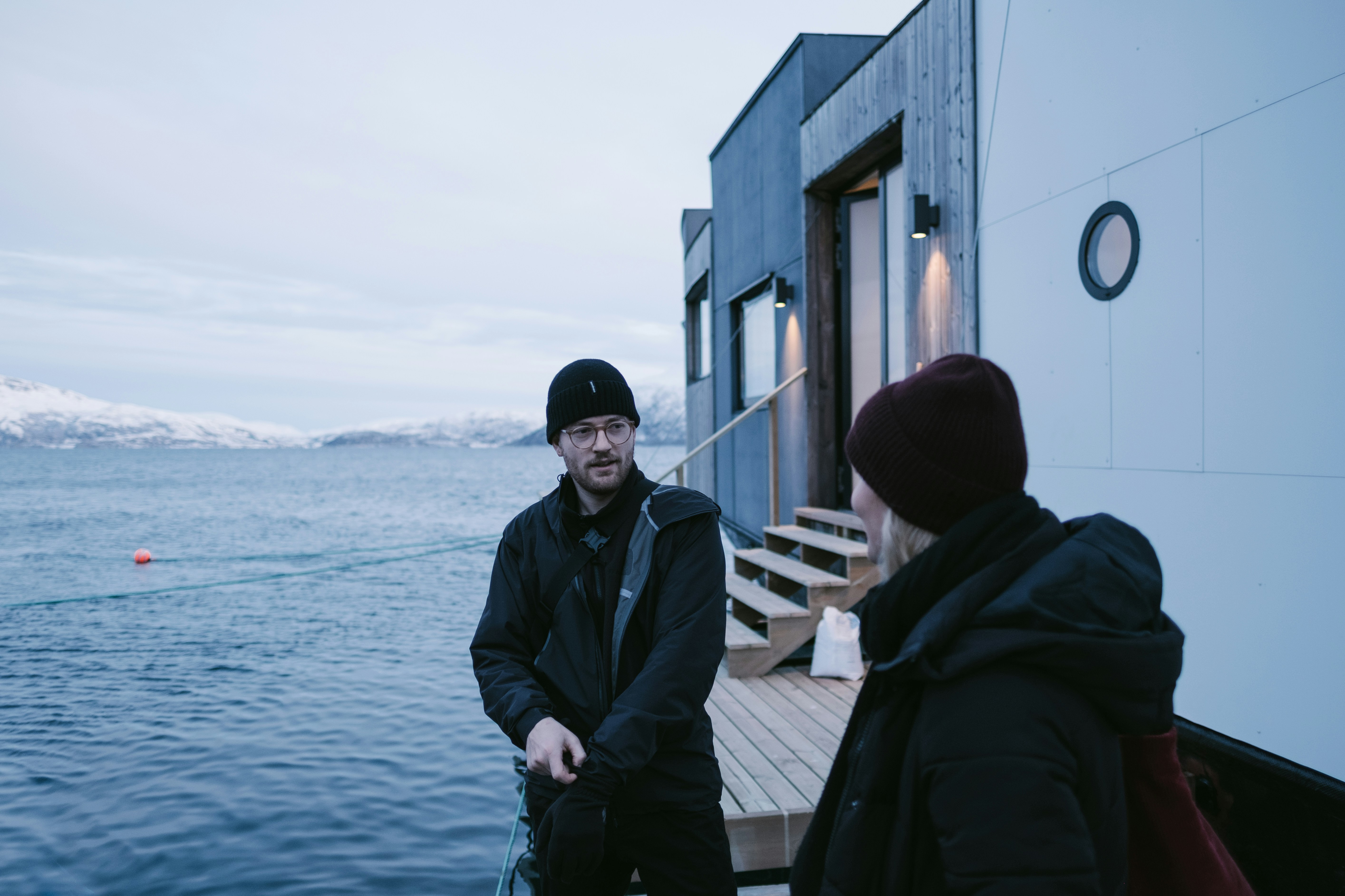 man in black jacket standing on wooden dock during daytime
