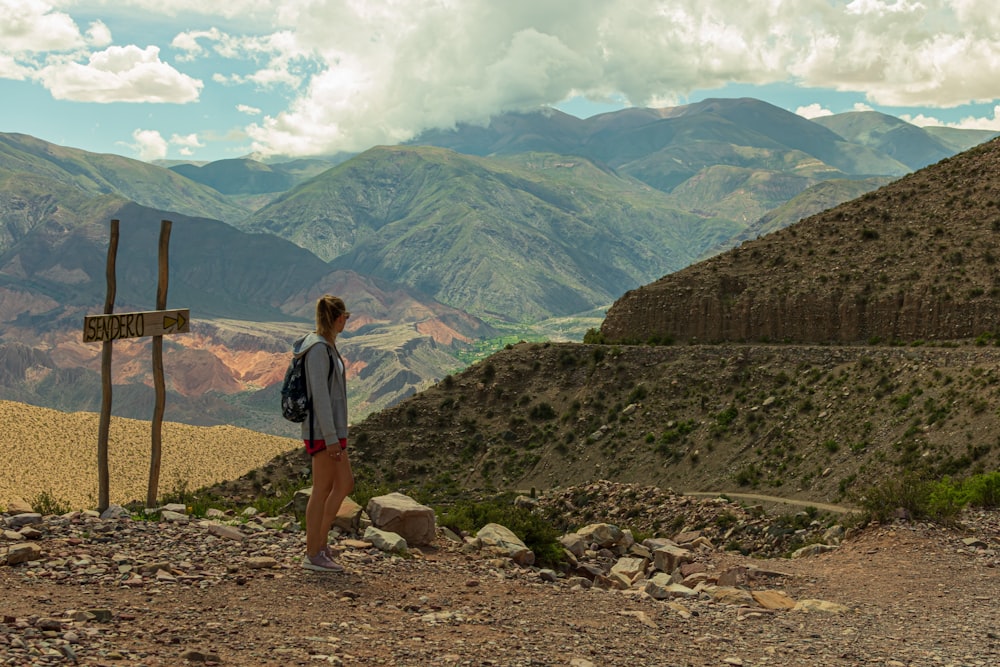 woman in black shirt and blue denim shorts standing on rocky ground during daytime