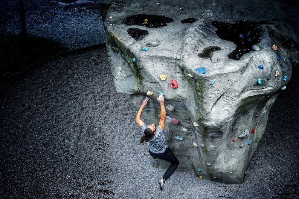 woman in black tank top and black pants climbing on gray rock