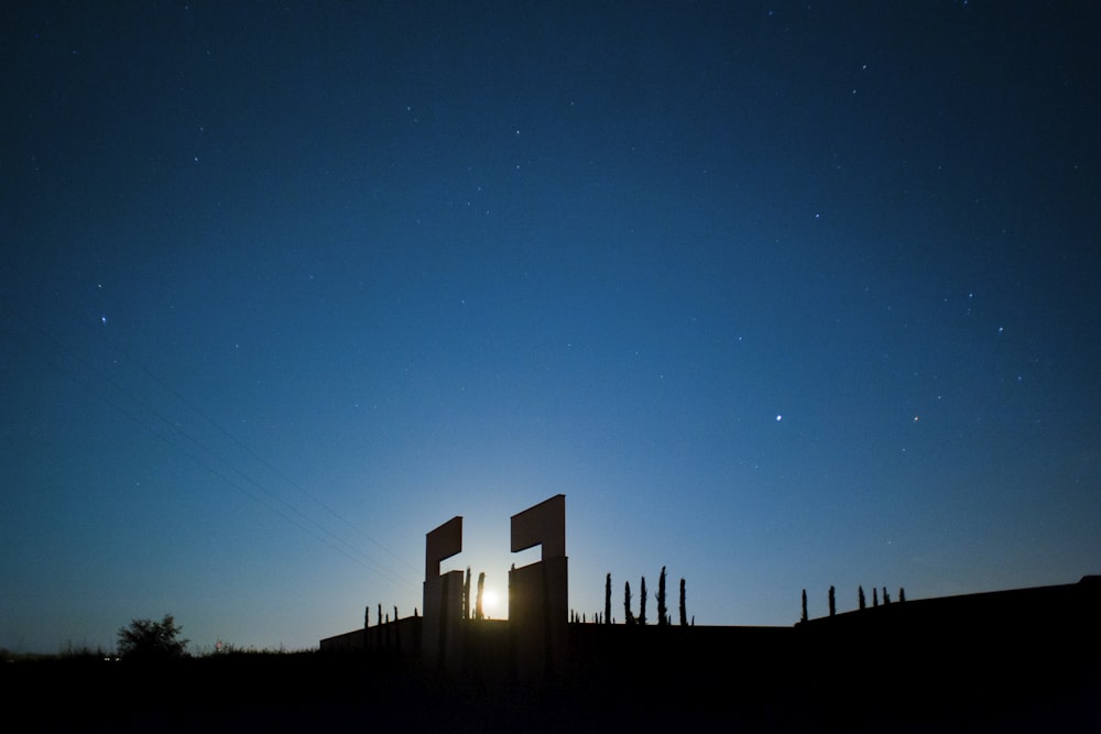 silhouette of building under blue sky during night time