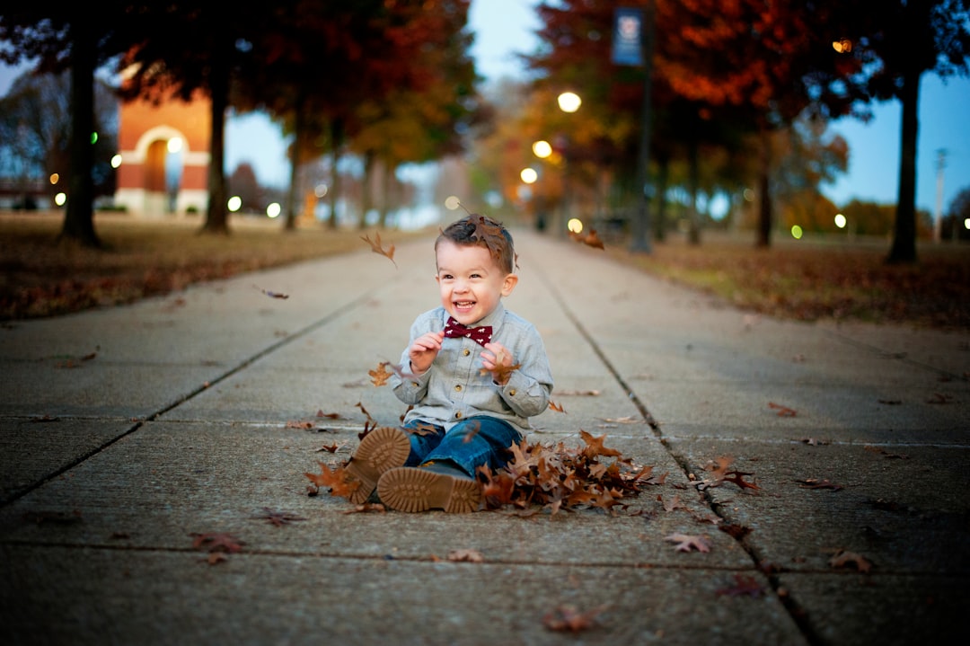 baby in white long sleeve shirt sitting on gray concrete pavement during daytime