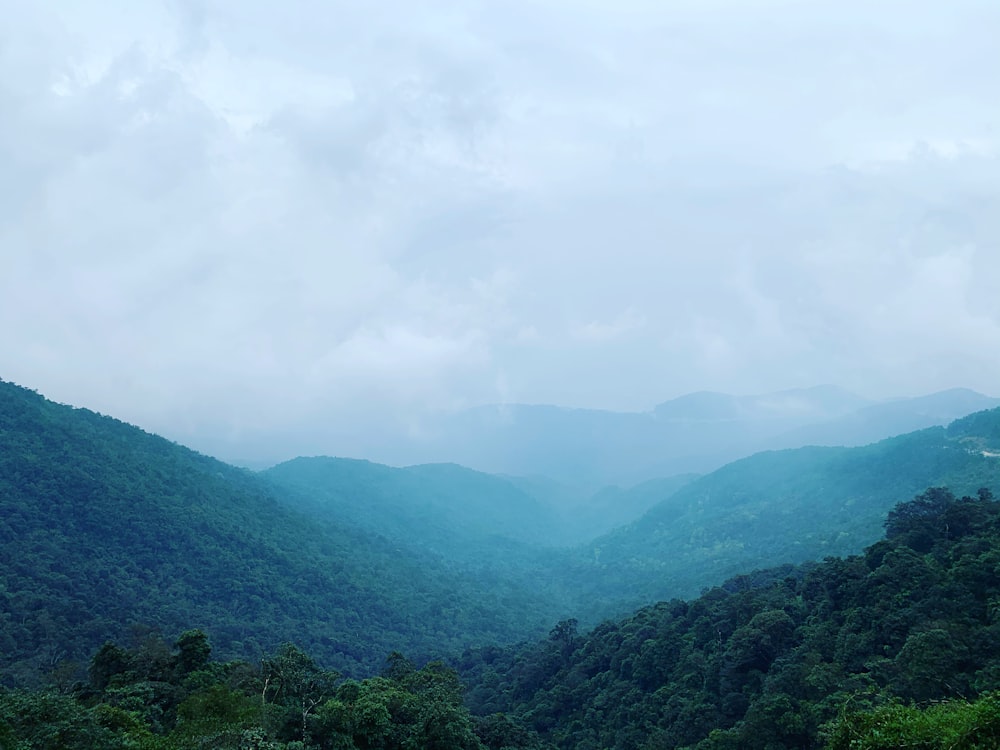 Montañas verdes bajo nubes blancas durante el día