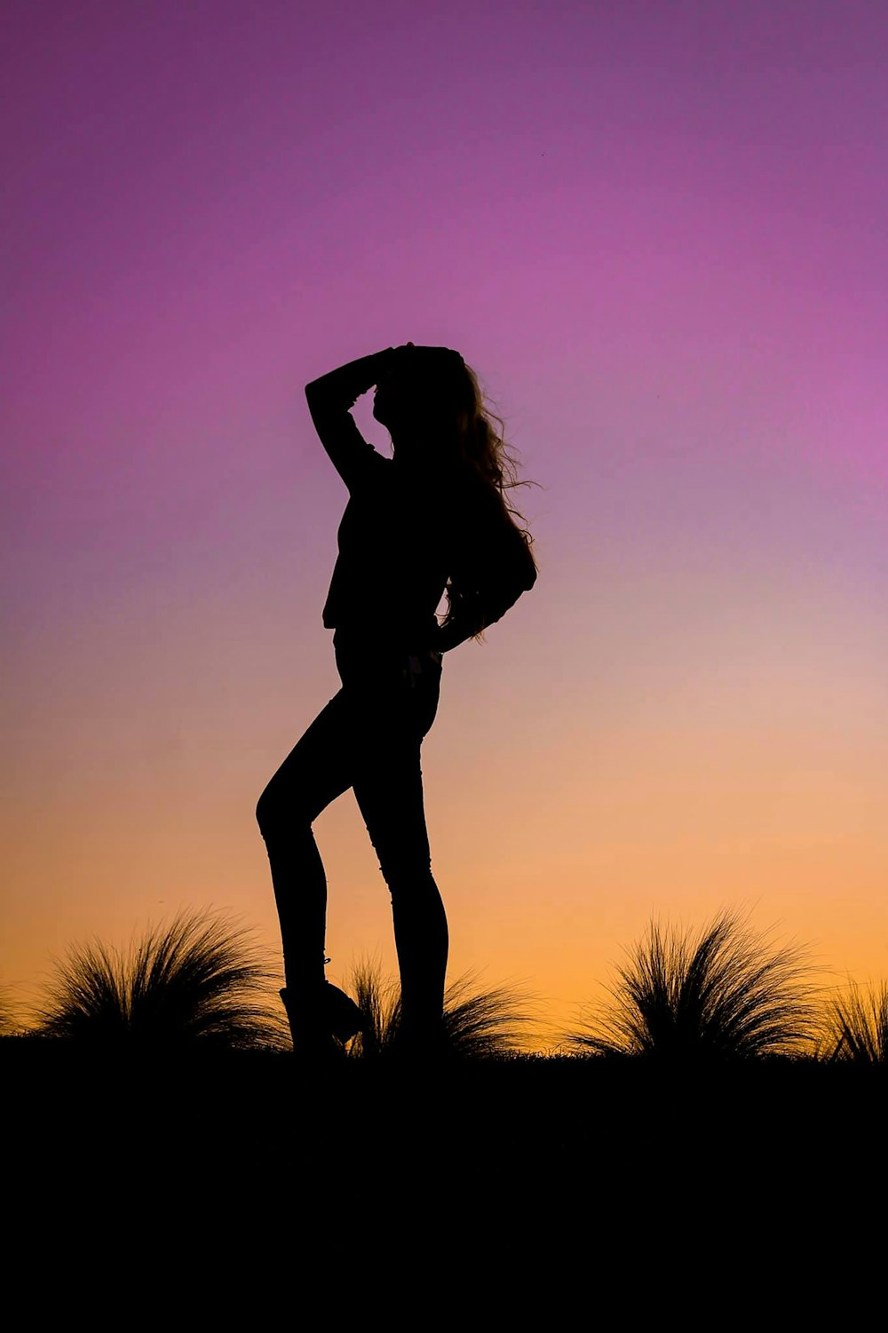 silhouette of woman standing on tree branch during sunset