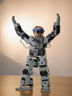 gray robot action figure on brown wooden table