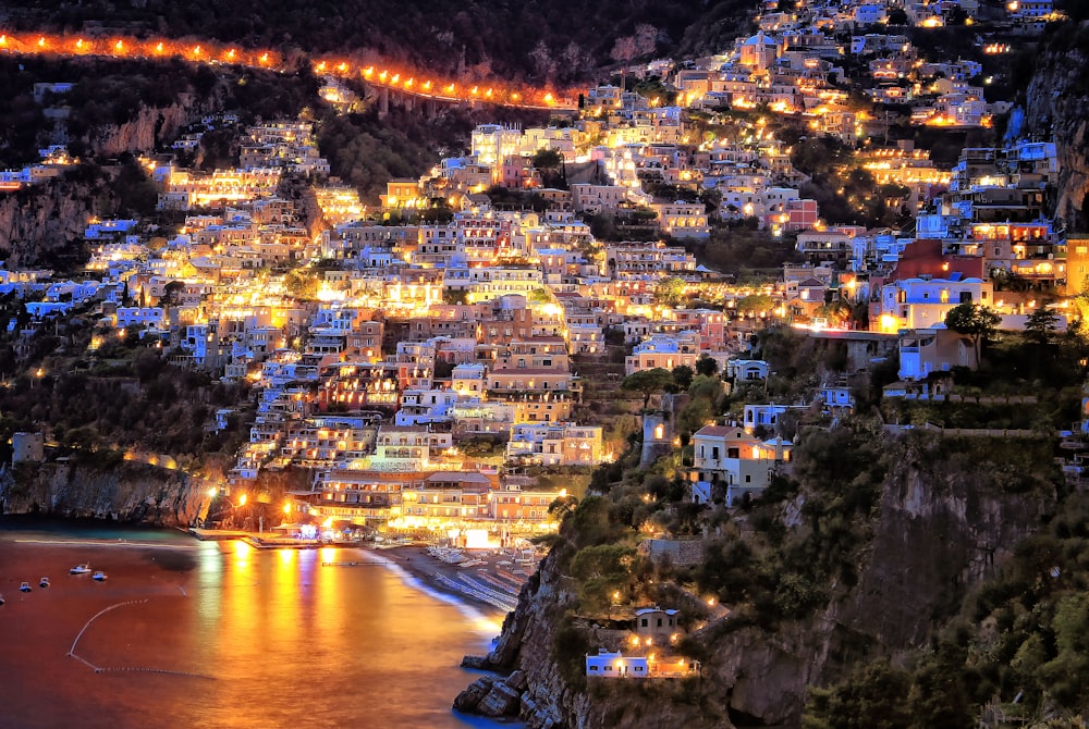 city lights on mountain near body of water during night time