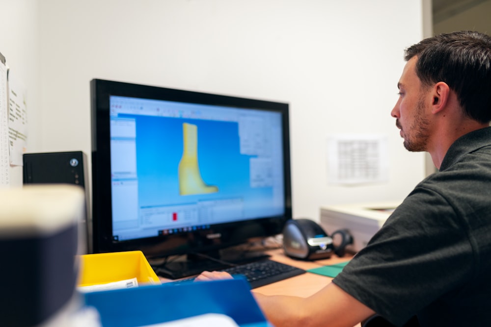 man in black t-shirt sitting in front of computer