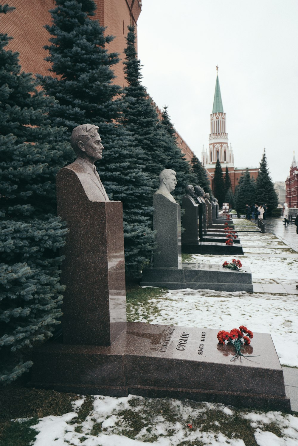 gray concrete statue near red flowers