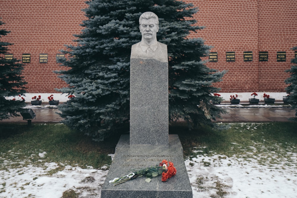 gray concrete statue near red brick building