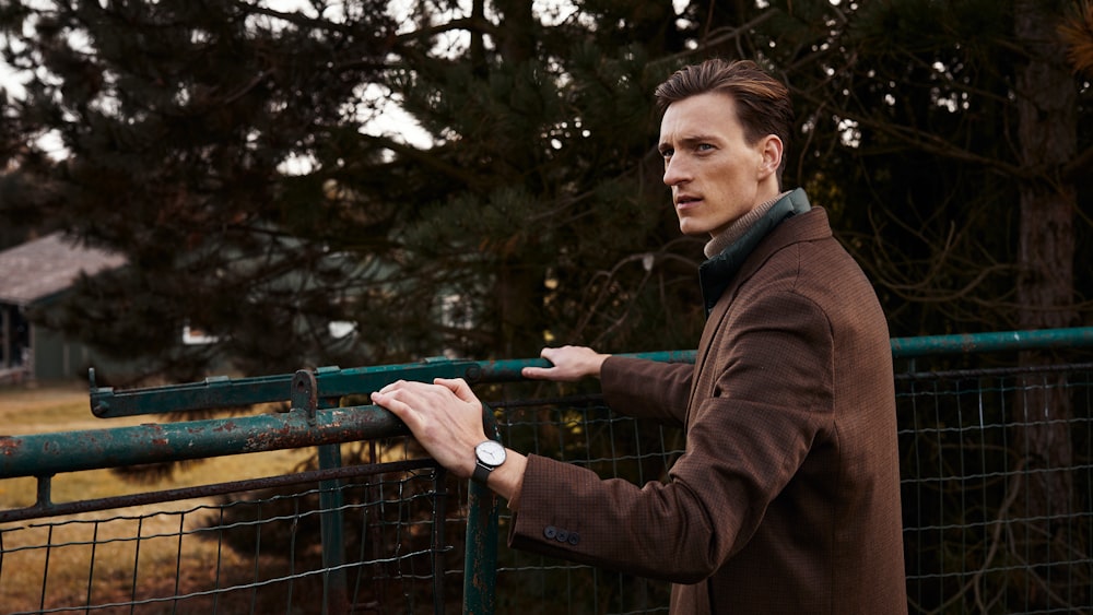 man in brown coat holding blue metal bar