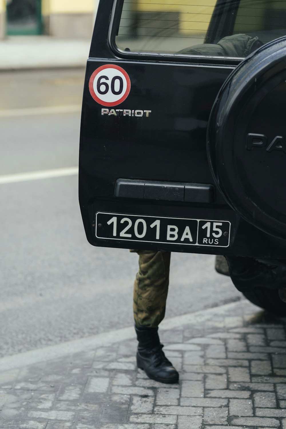 man in black jacket and brown pants standing on road during daytime