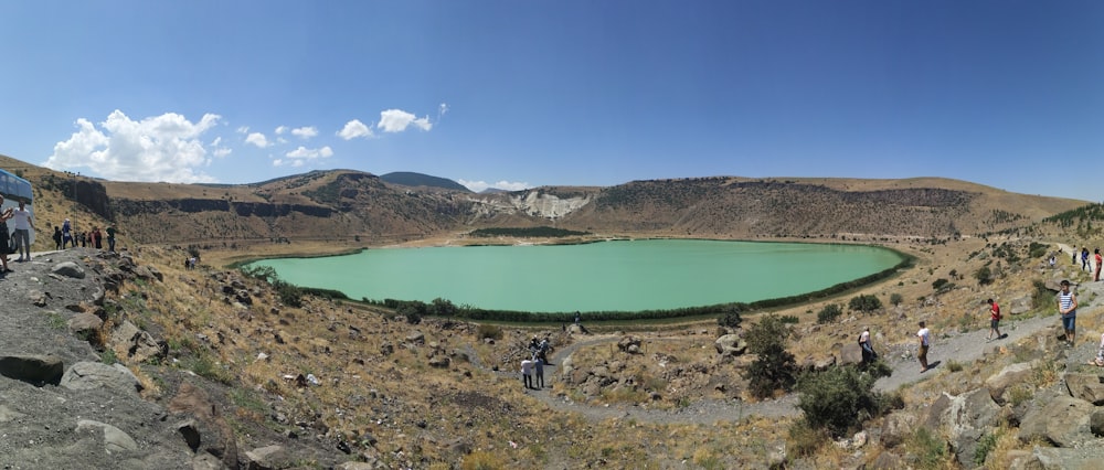 person in black jacket and black pants standing on brown field near lake during daytime