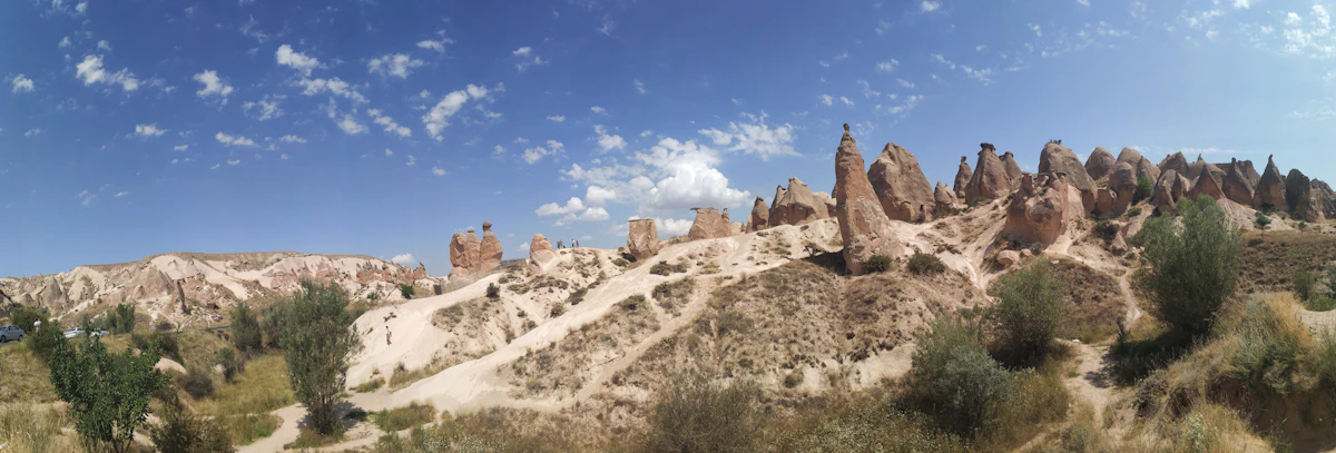 Pale rock spires and scrub on a hillside near Ürgüp under a blue sky